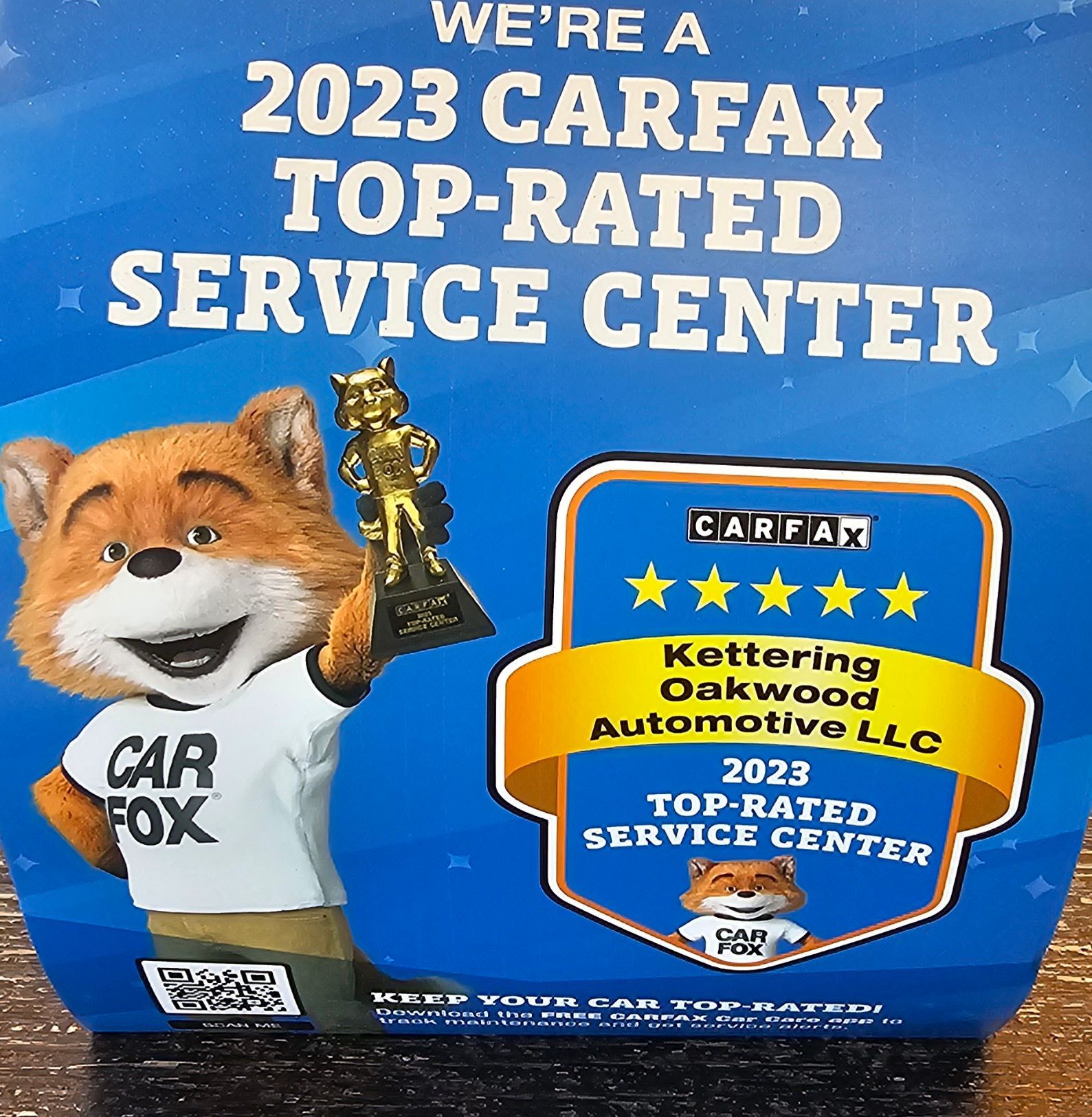 Carfox mascot holding trophy, next to a Carfax Top-Rated Service Center award for Kettering Oakwood Automotive LLC.