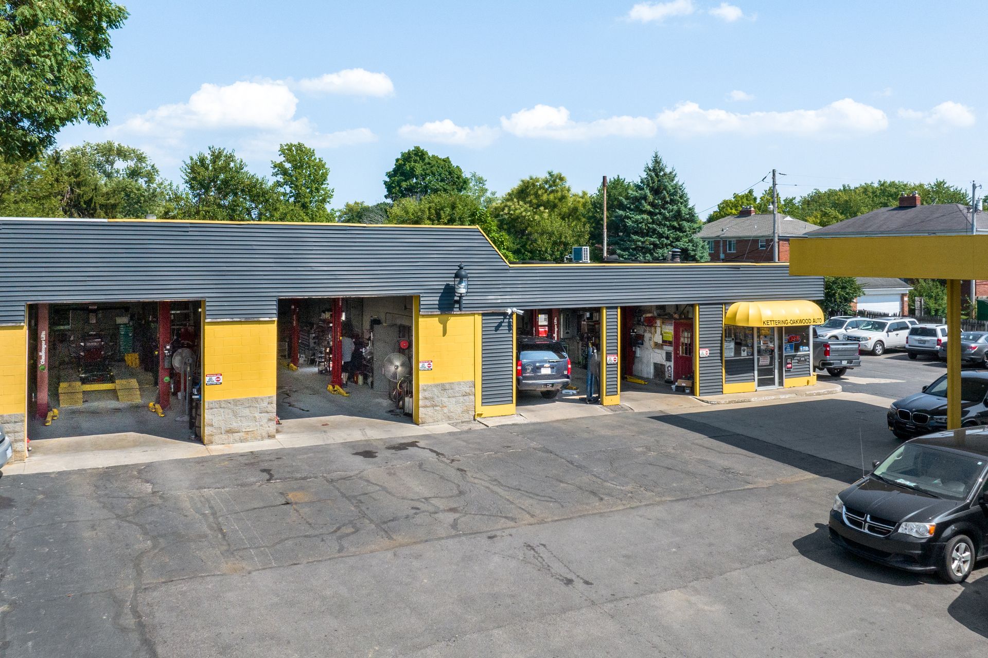 Auto repair shop with open bays, yellow accents, and cars being serviced.