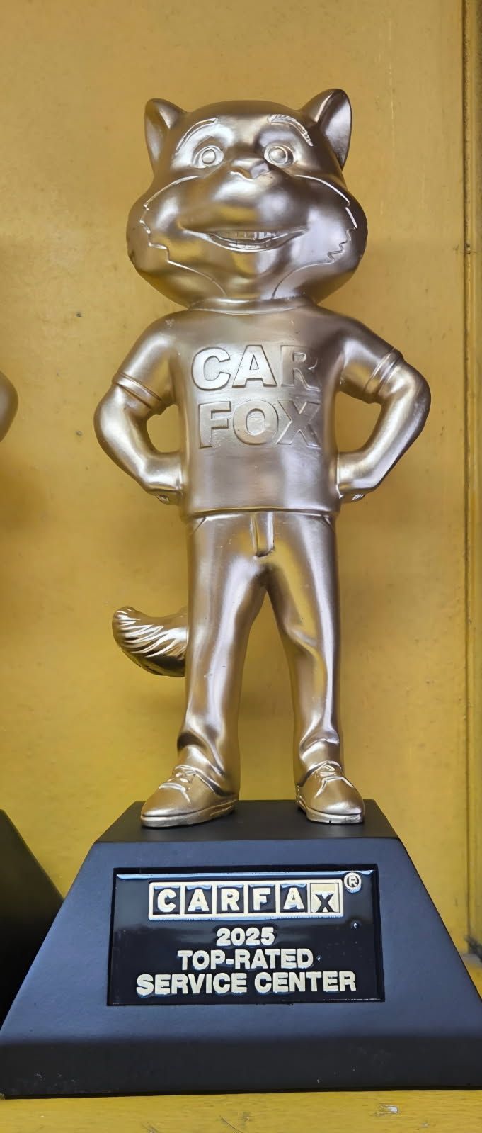 Silver trophy of a smiling cat mascot on a black base labeled “CARFAX Top Dog Service Center.”