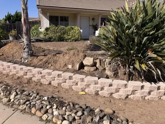 A brick wall is being built in front of a house.