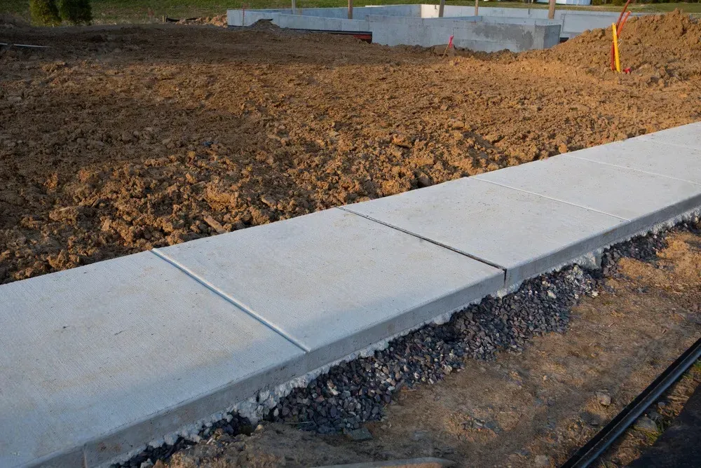A concrete sidewalk is being built in a dirt field