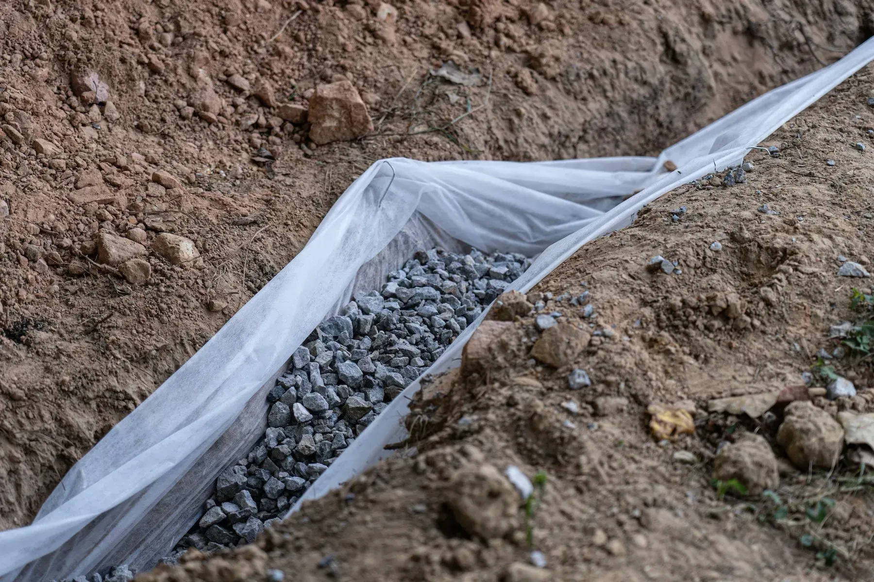 A bag of gravel is sitting on top of a pile of dirt.