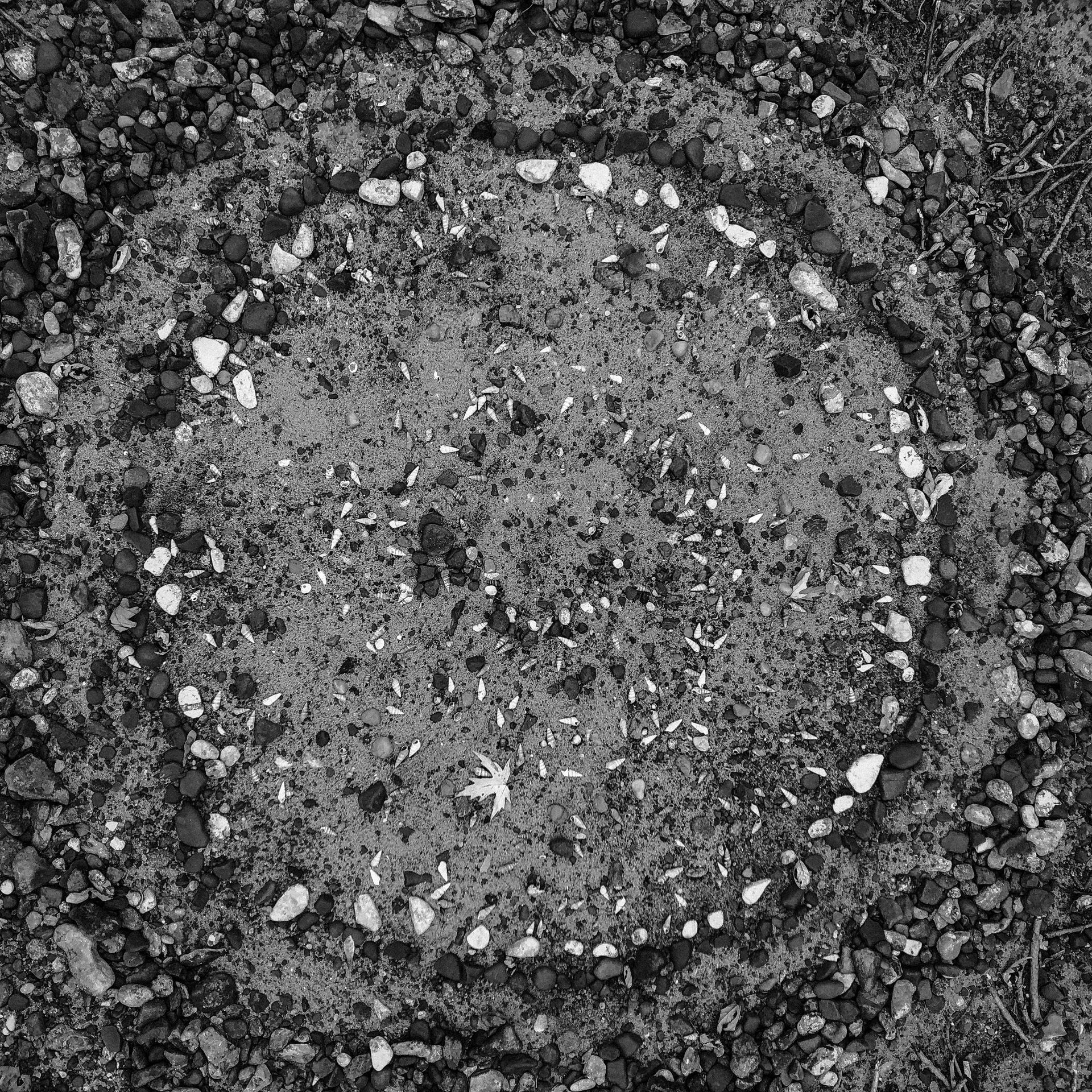 A black and white photo of a circle of rocks on the ground.