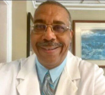 Dr. Frederick D. Sams, DMD, smiling in his white coat at Pittsburgh Dentistry in Shadyside