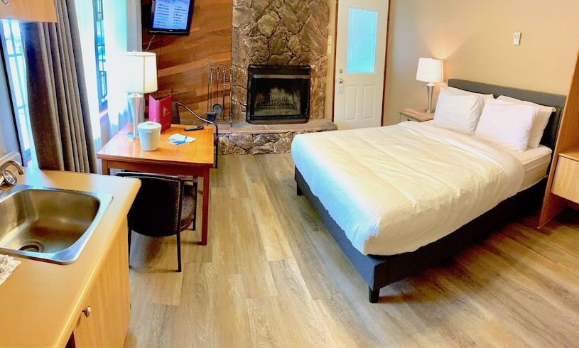 Cozy motel room with bed, fireplace, small kitchen, and table.