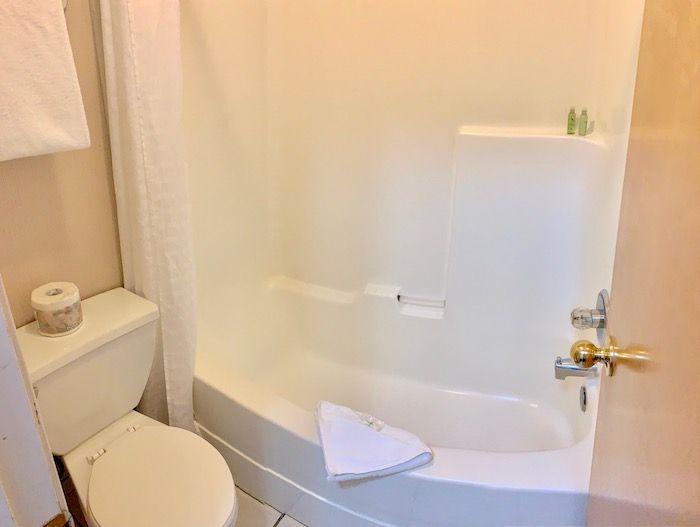 Bathroom with a white bathtub, toilet, and towel.