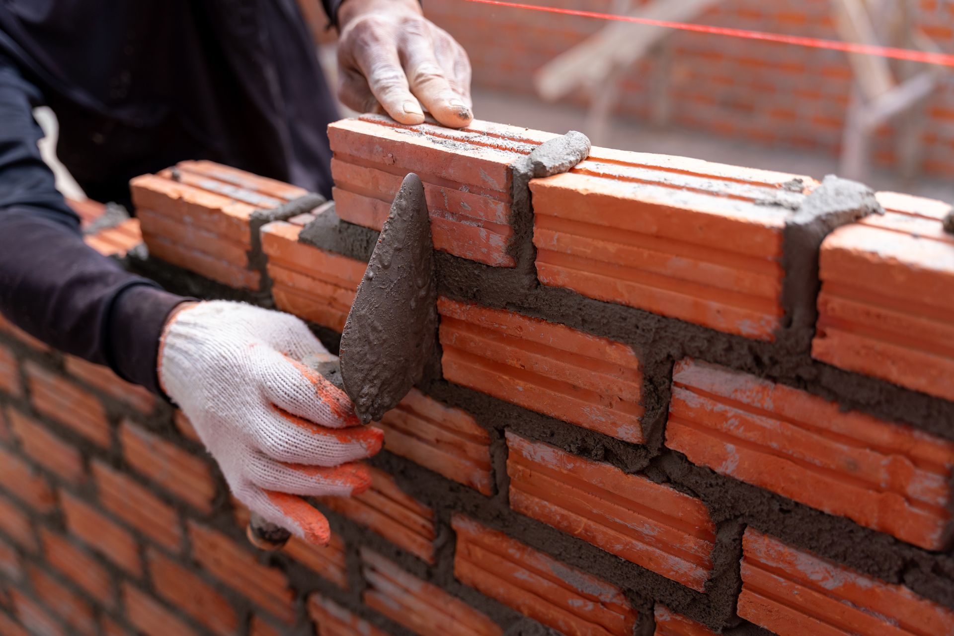 A Man Is Laying Bricks on A Wall with A Trowel | Saint Cloud, WI | Feldner Construction Inc.