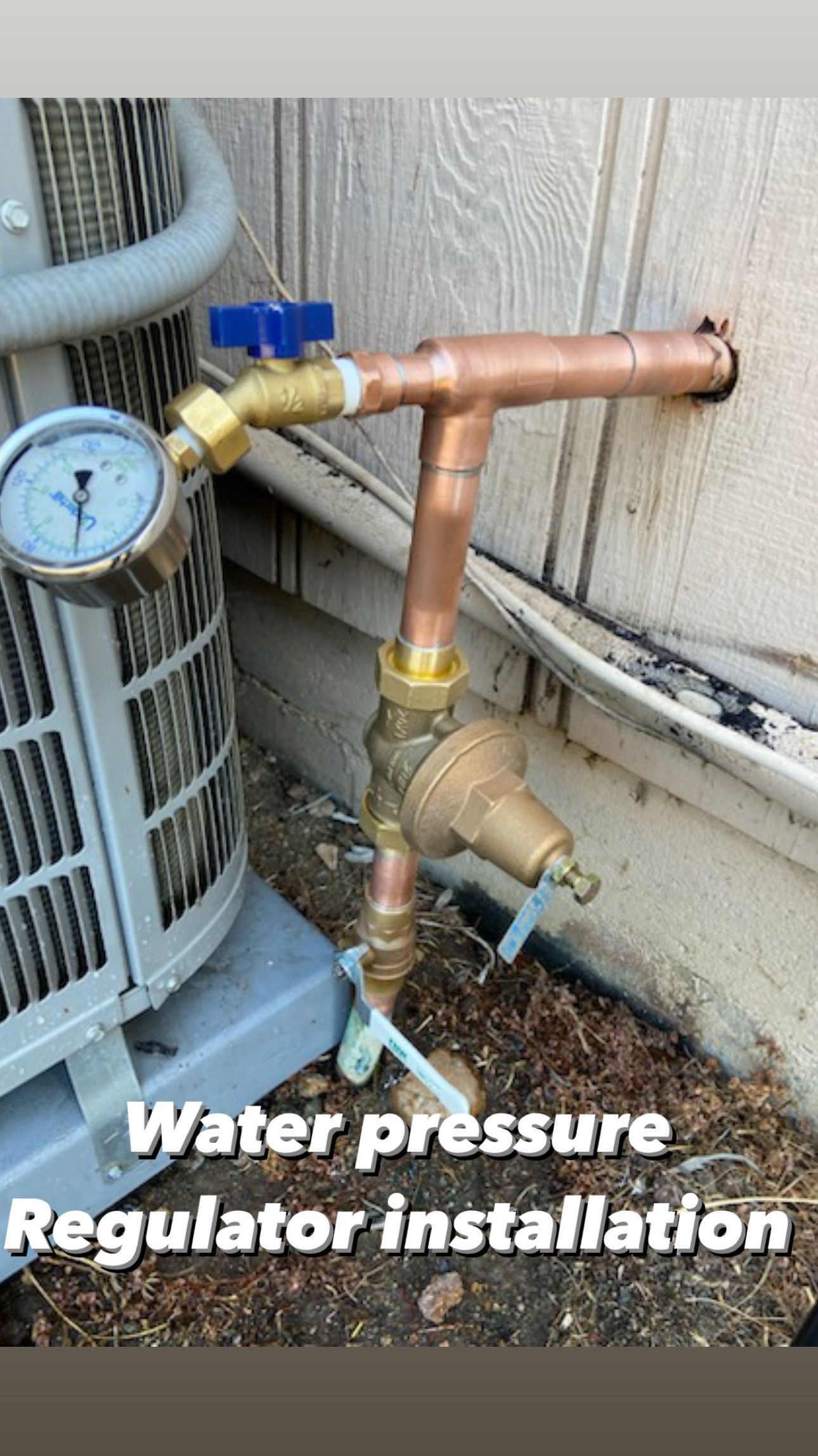 A water pressure regulator is being installed on the side of a building.