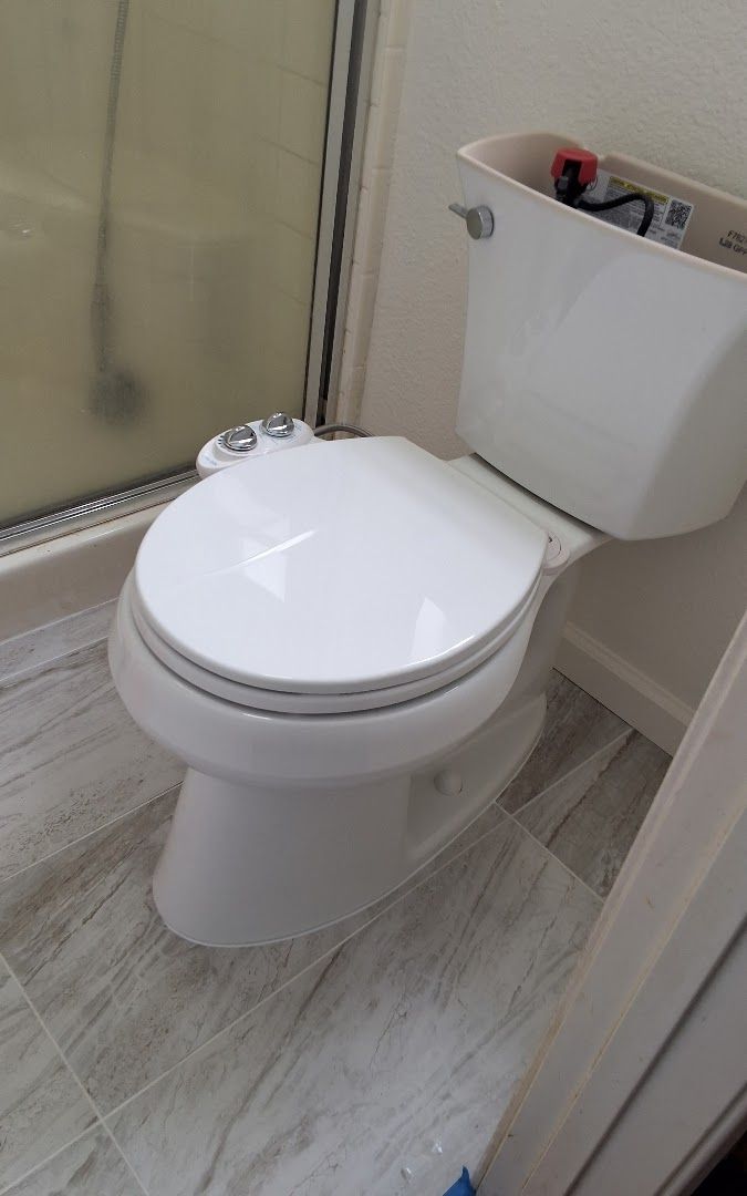 A white toilet is sitting in a bathroom next to a shower.