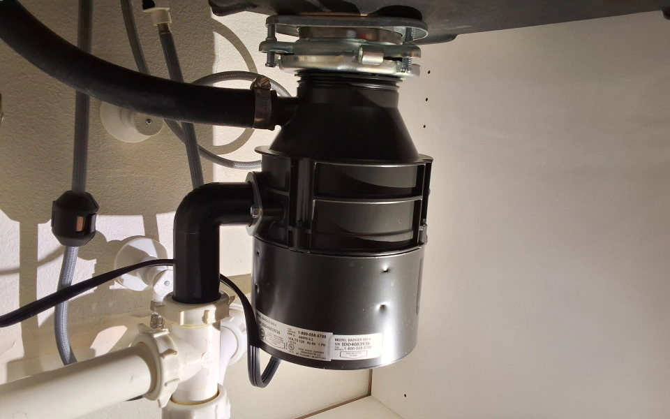 A garbage disposal is under a sink in a kitchen