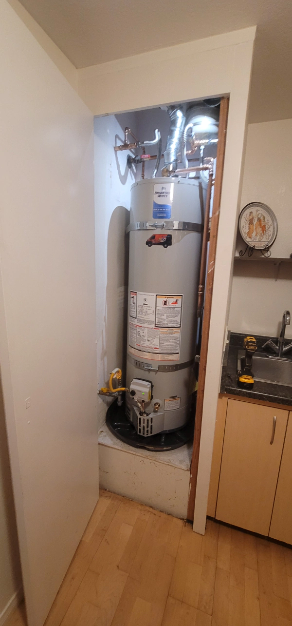 A water heater is sitting in a closet in a kitchen.