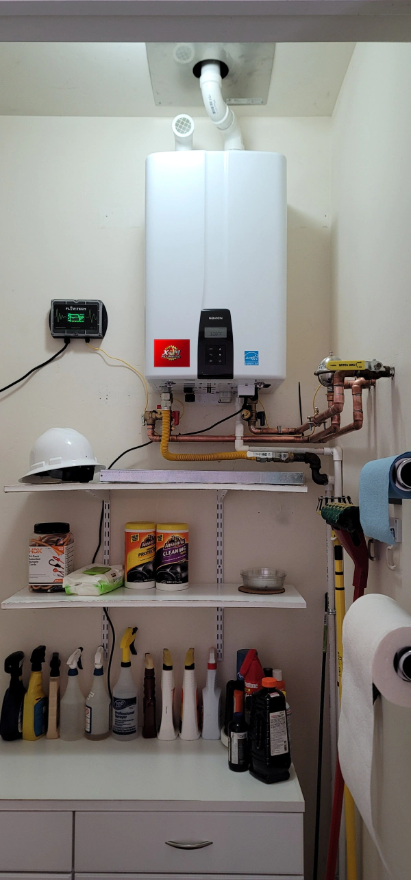 A white boiler is sitting on top of a shelf in a laundry room.