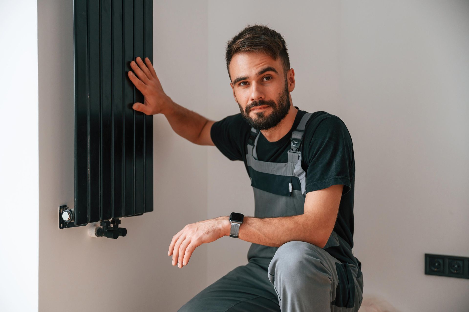 Heating contractor inspecting modern vertical radiator during maintenance. Heating contractor inspecting modern vertical radiator during maintenance.