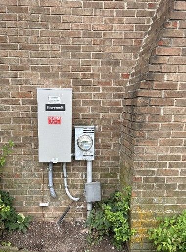 Electrical equipment mounted on brick wall, including a panel and meter. Electrical equipment mounted on brick wall, including a panel and meter.