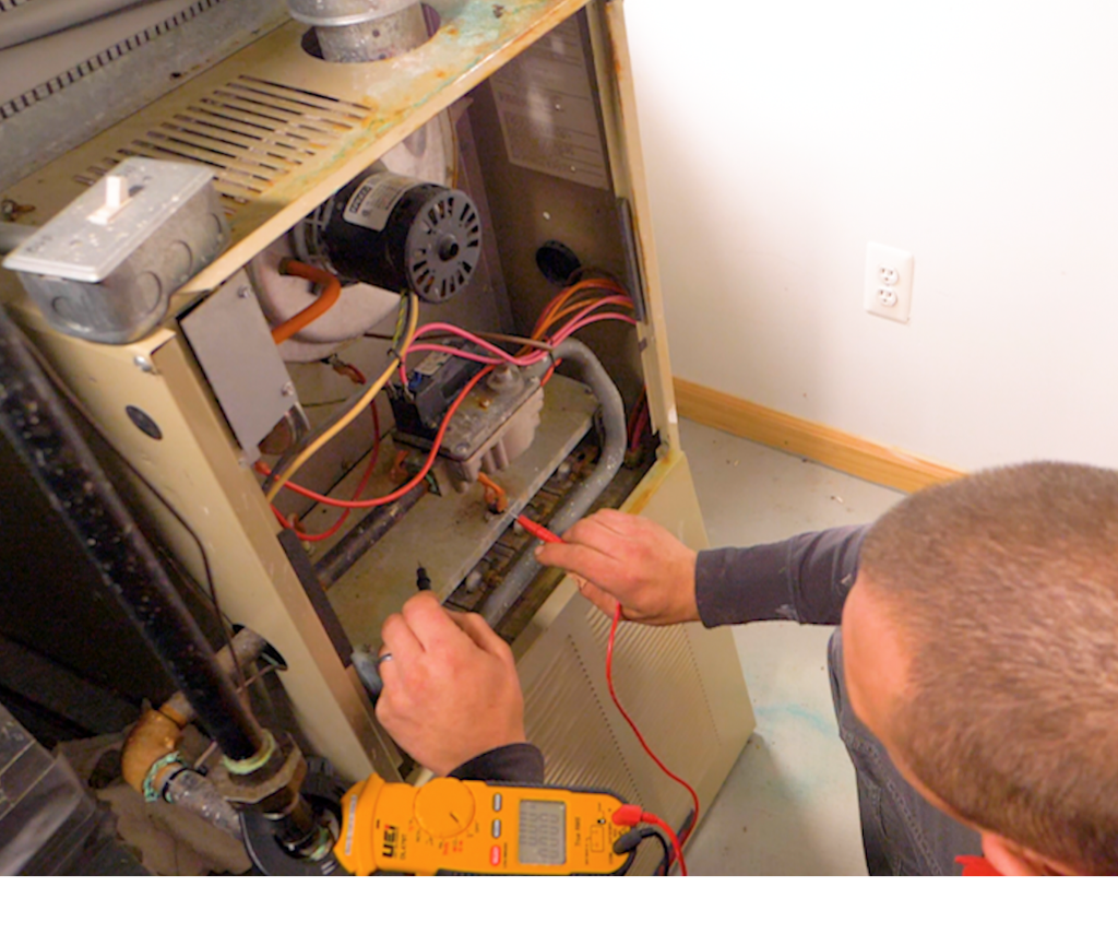 Technician testing an older model furnace. Technician testing an older model furnace.
