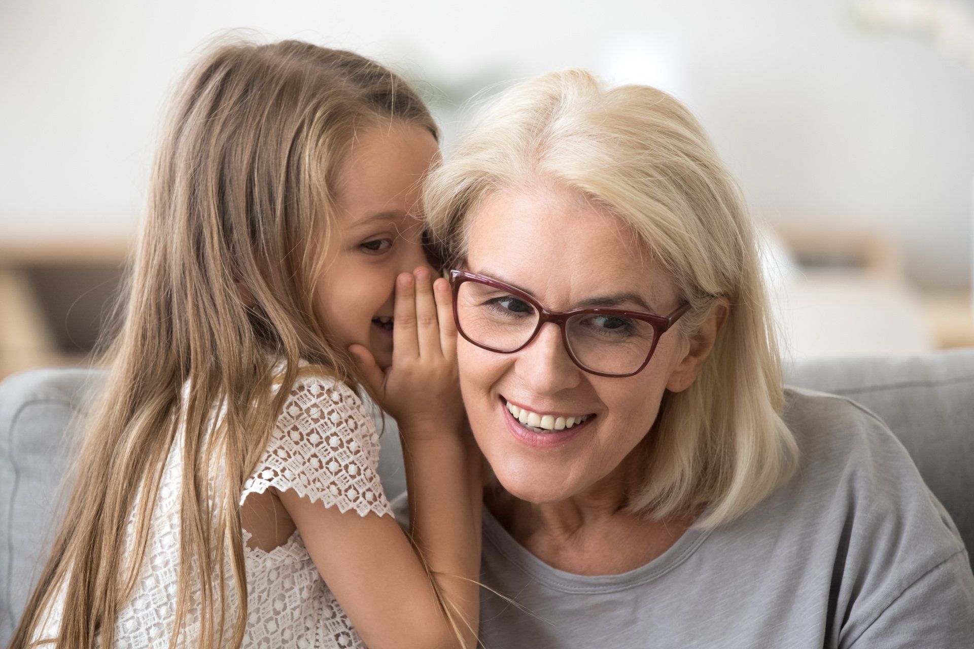 kleines Mädchen flüstert Ihrer Oma etwas ins Ohr