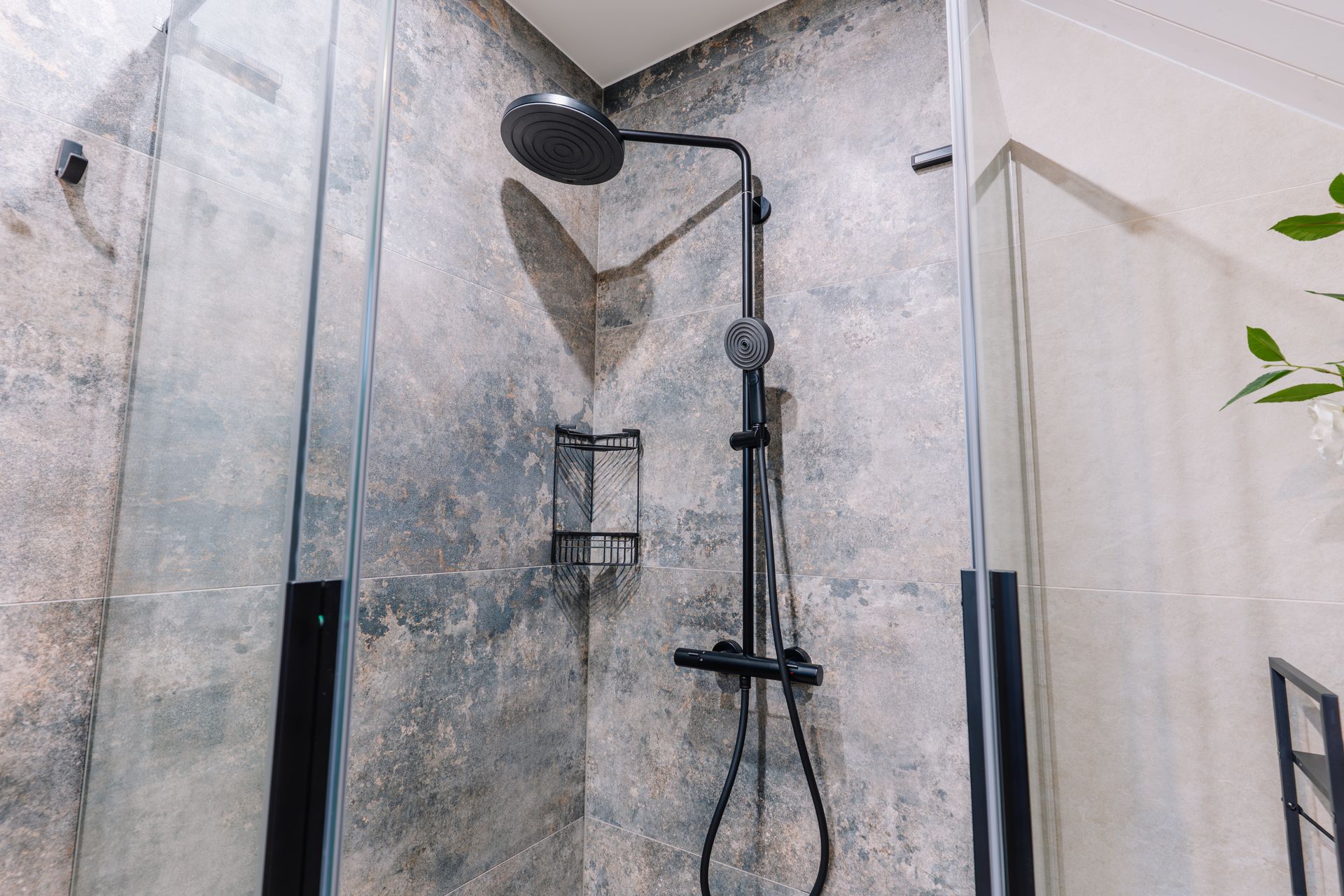 Modern shower enclosure with black fixtures and gray tiled walls