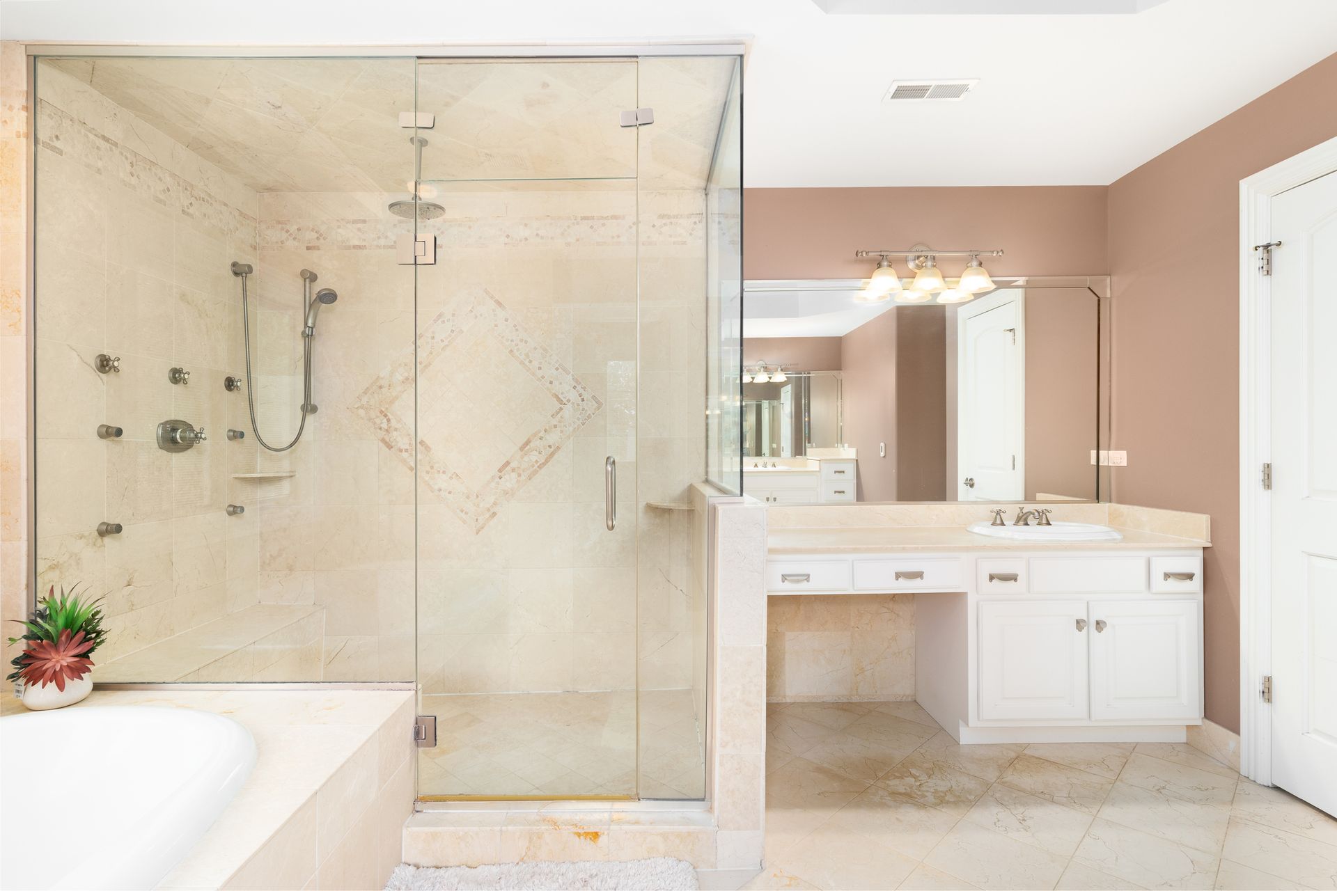 A beautiful bathroom with a glass shower door, bathtub, white vanity cabinet, and mirror.