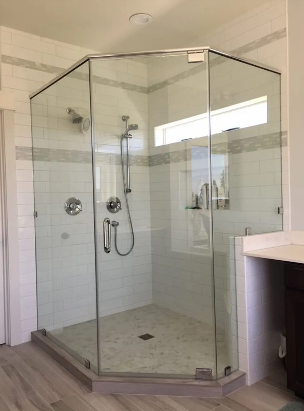 A standing shower in the corner of a bathroom, encased by glass shower doors. A standing shower in the corner of a bathroom, encased by glass shower doors.
