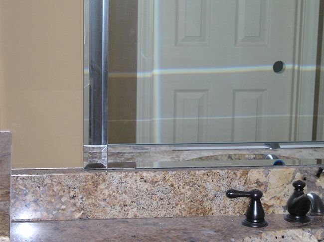 Bathroom with granite countertop, mirror, and black faucet. Door reflected in the mirror.
