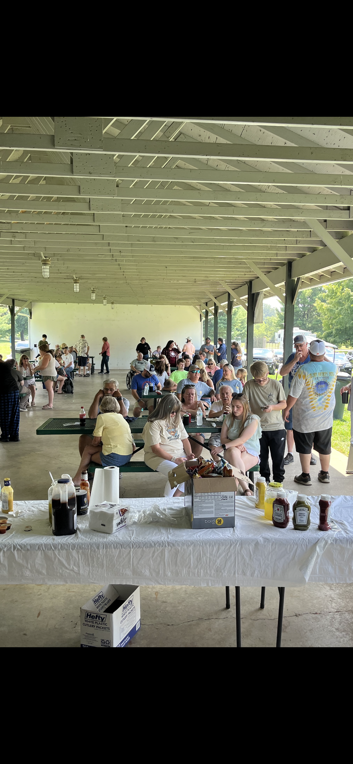 A group of people are sitting at tables in a pavilion.