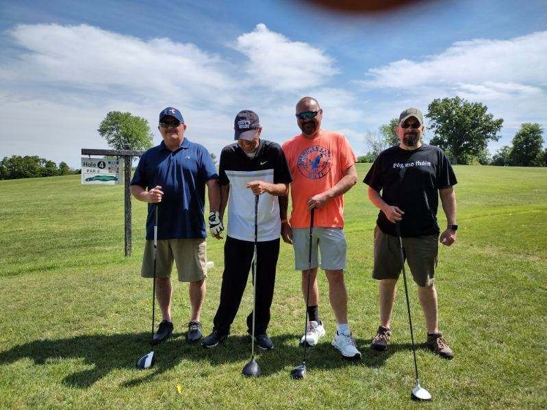 A group of men are standing on a golf course holding golf clubs.