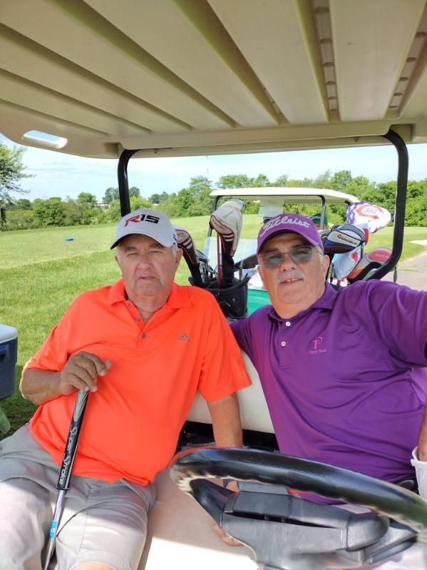 Two men are sitting in a golf cart on a golf course.