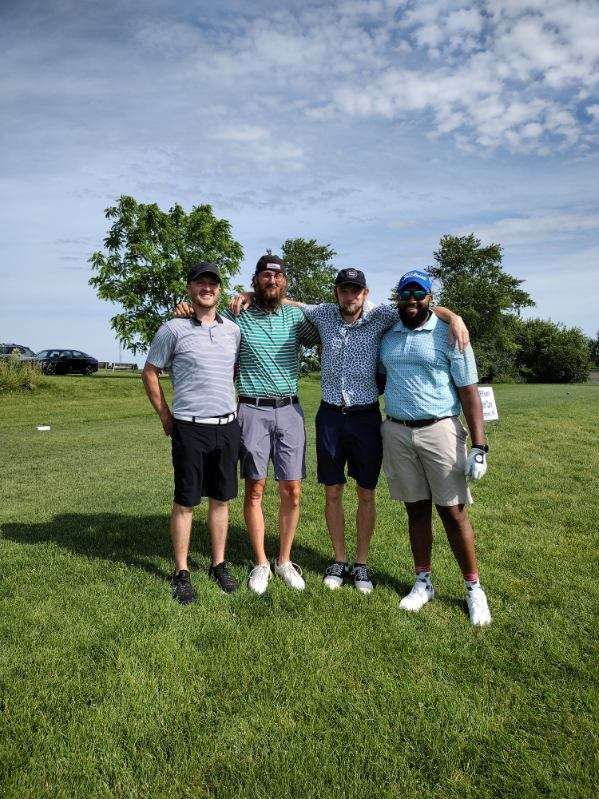 A group of men are posing for a picture on a golf course.