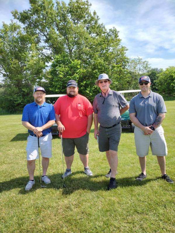 A group of men are standing next to each other on a golf course holding golf clubs.