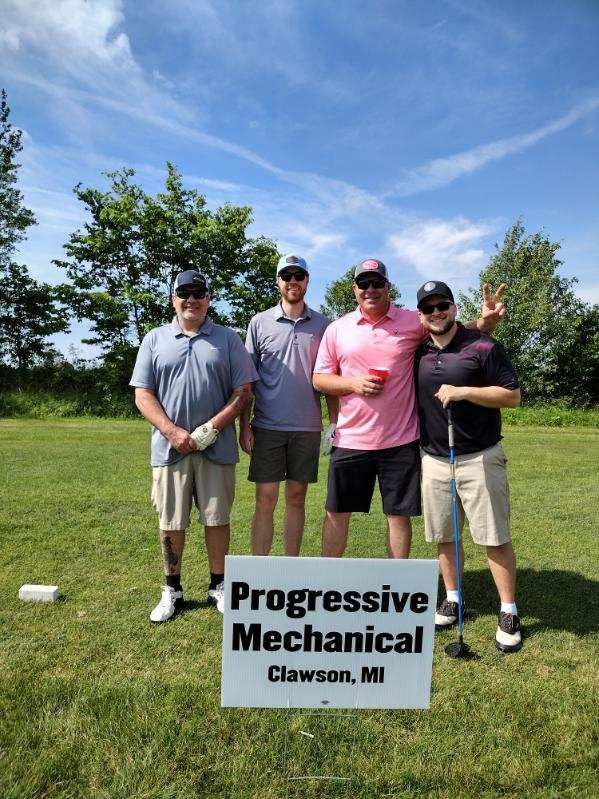 A group of men standing next to a sign that says progressive mechanical.