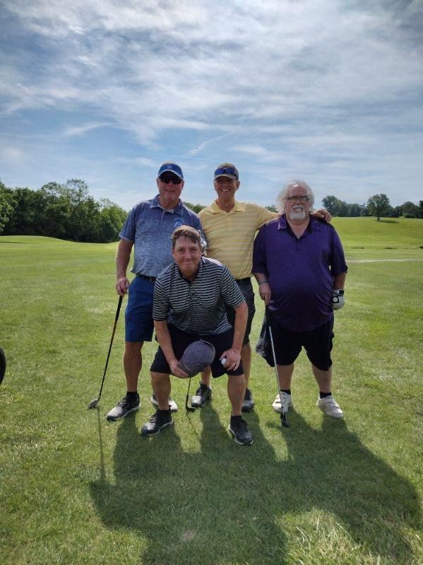 A group of men are posing for a picture on a golf course.