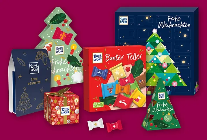 Verschiedene festliche Schokoladengeschenkboxen und baumförmige Leckereien in roter, grüner und blauer Verpackung