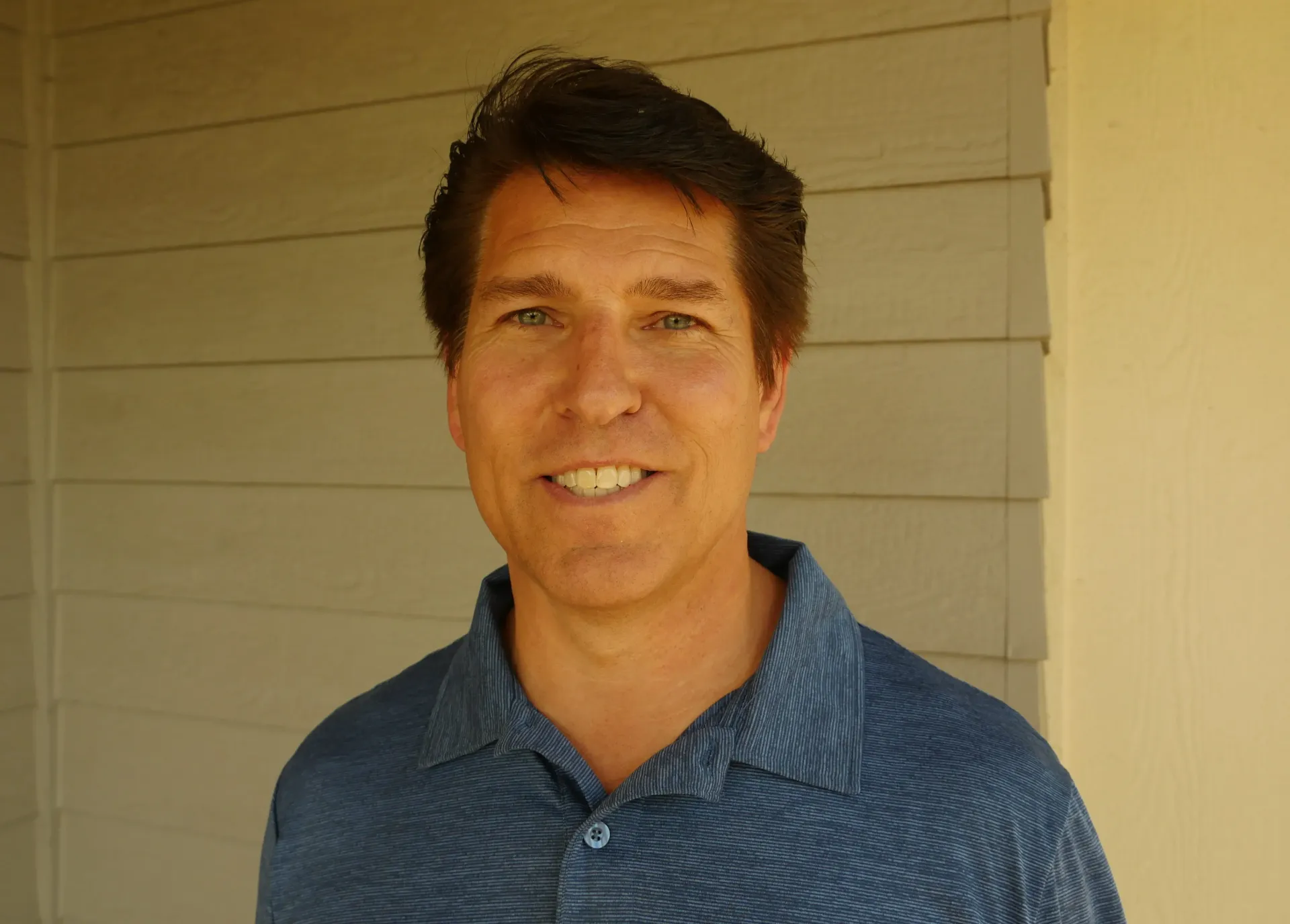 Brandy Straub owner of Redwood Empire Termite & Pest Control in a blue shirt is smiling in front of a white wall.