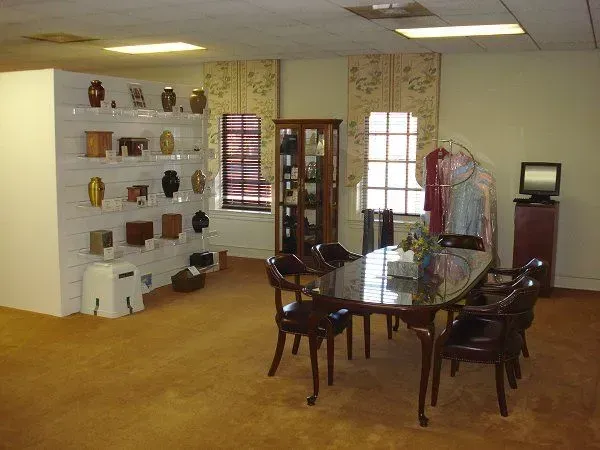 Empty showroom with wooden table and chairs, display shelves, clothing rack, and TV on a stand.