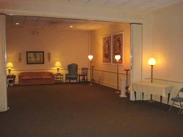 Empty room with carpet, chairs, tables, and soft lamp lighting