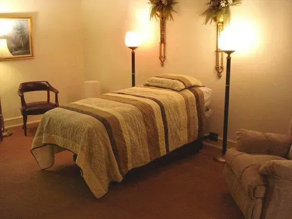 Room with a treatment table, lamp stands, chair, and couch in warm lighting