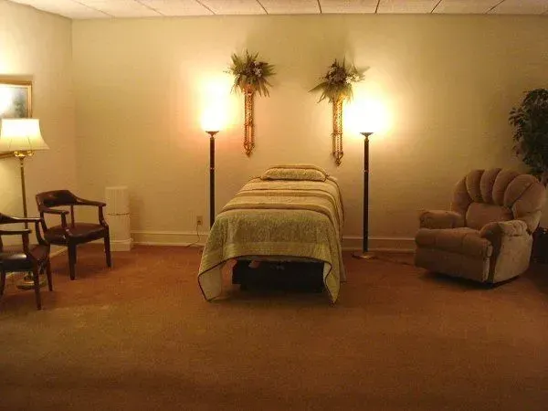 Warm room with a single bed, two lamps, a chair, and a recliner against beige walls