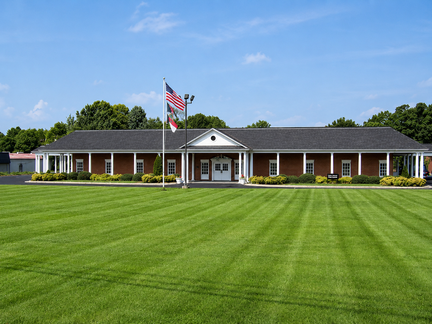 Brick building with American flag and sign reading “Palmer-Marler” on a sunny lawn.