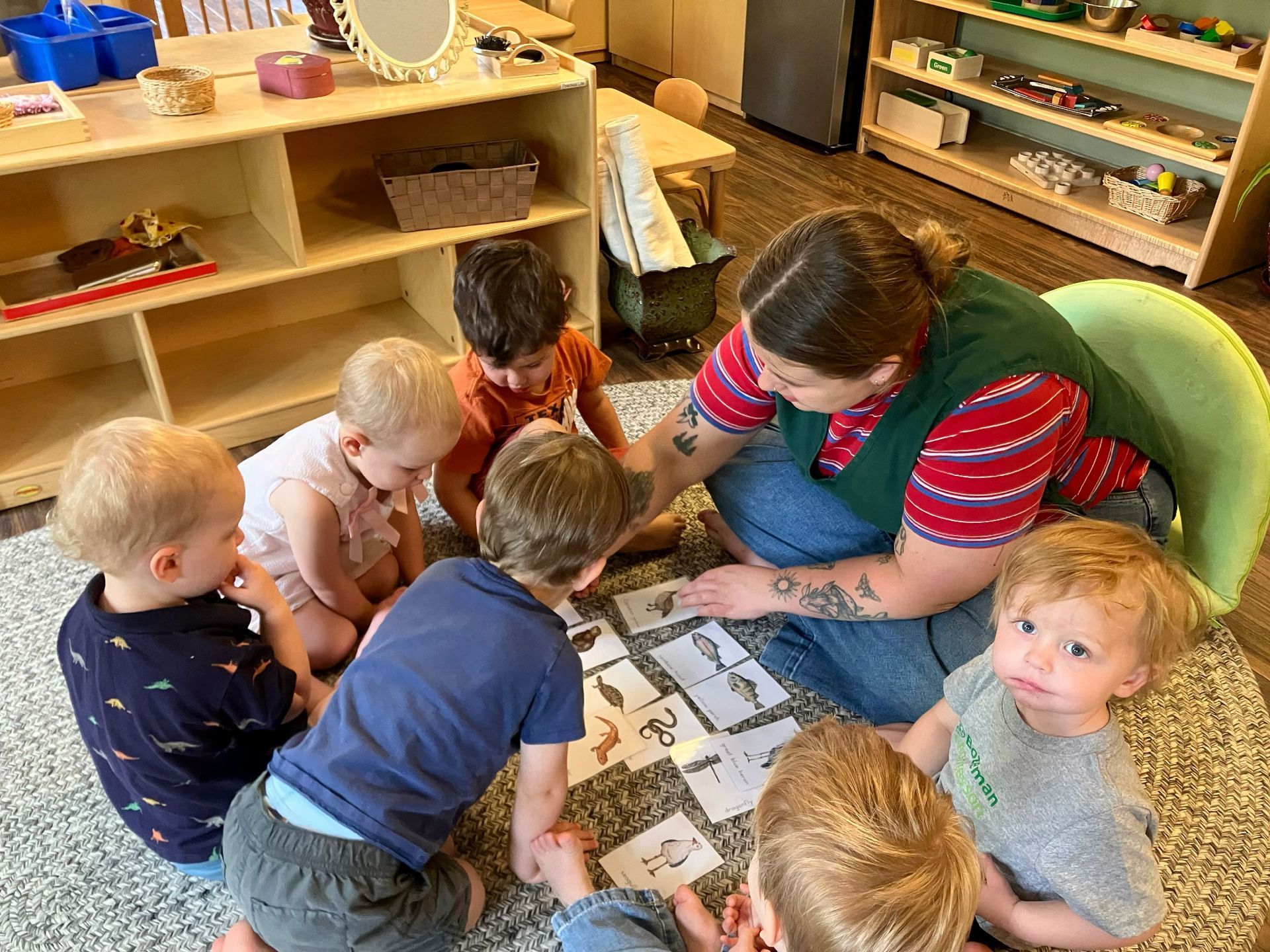 Teacher helping children at a table with a board game in a classroom