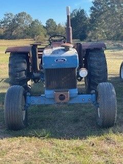 A blue ford tractor is parked in a grassy field.