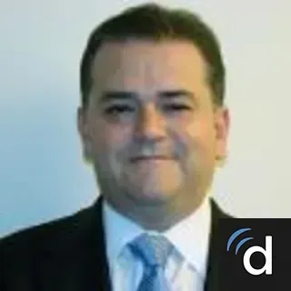Man in a suit smiles, soft lighting.