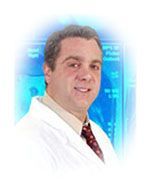 Man in white coat, smiling, against a blue, tech-filled background. He wears a tie.