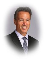Man in a suit smiles, headshot with gradient background.