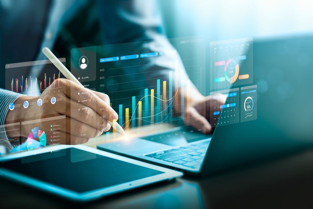 Hands using a tablet and laptop with glowing analytics charts on screen