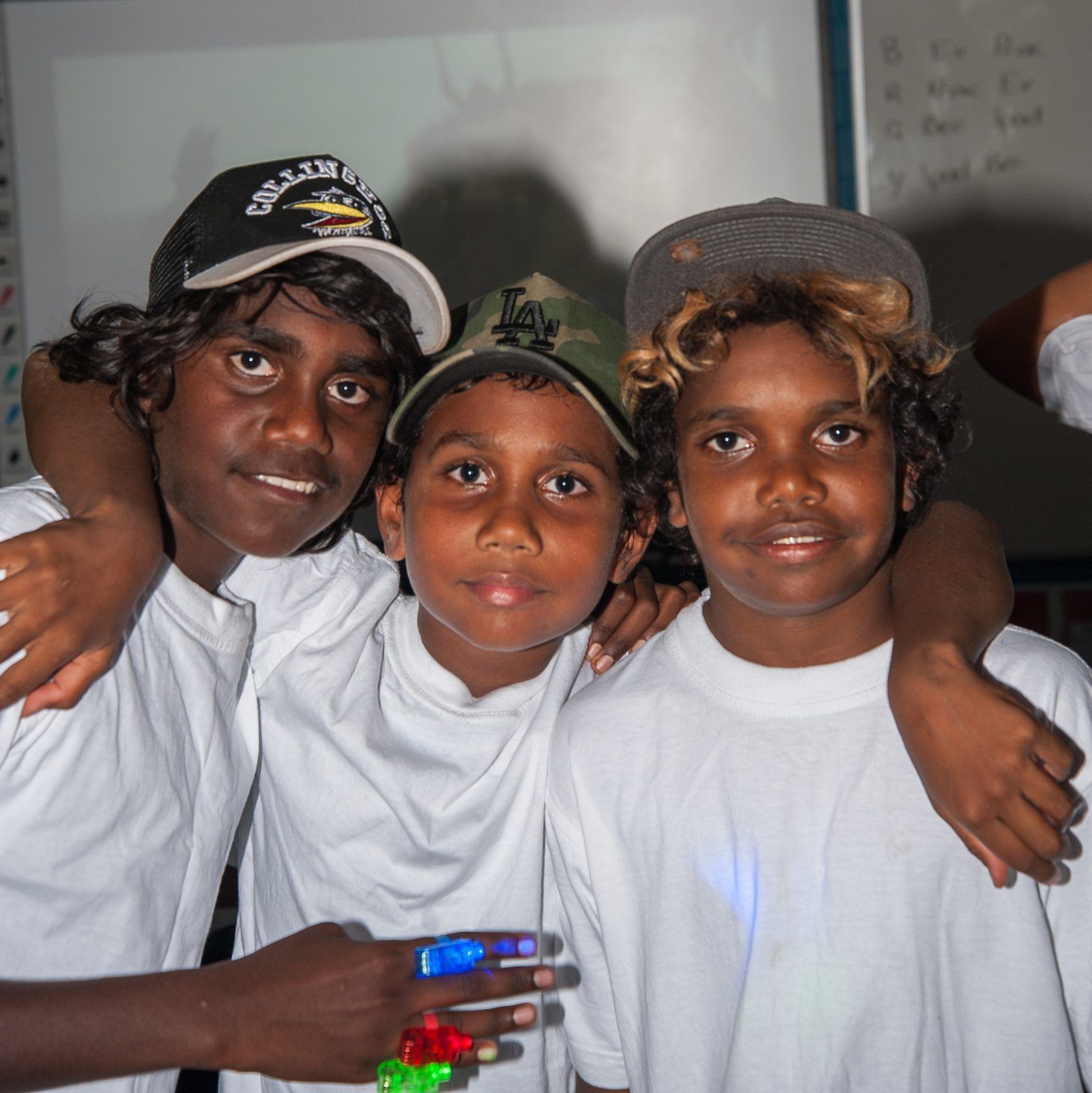 A group of young boys posing for a picture with one wearing a hat that says dolphins