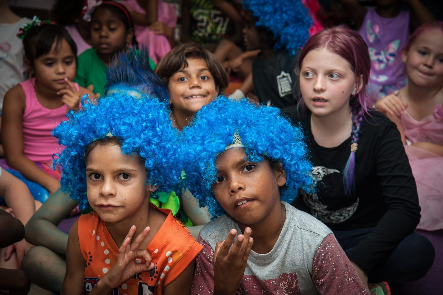 A group of children wearing blue wigs are posing for a picture