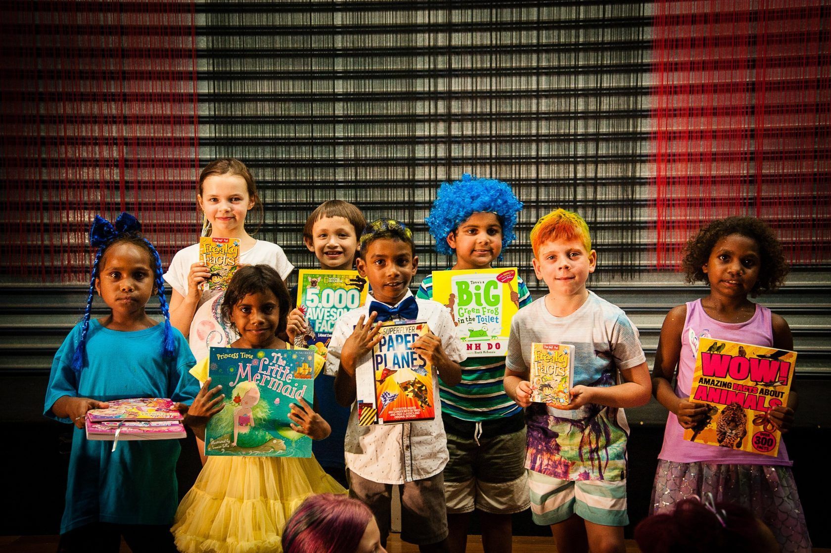 A group of children are posing for a picture while holding books.