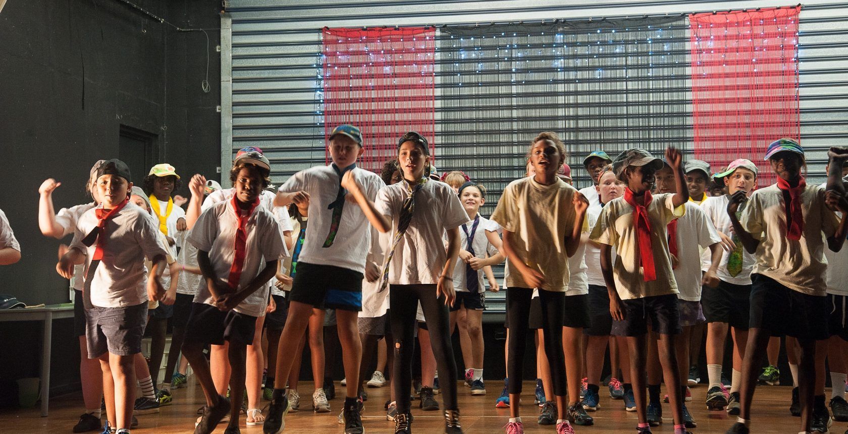 A group of children are standing on a stage in front of an american flag.