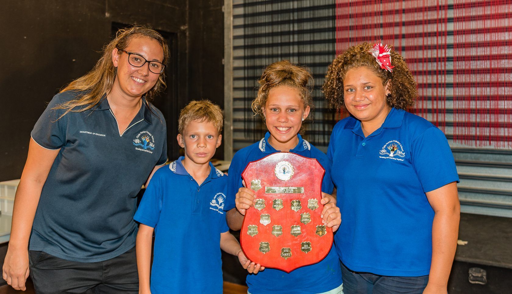 A woman and three children are standing next to each other holding a plaque.