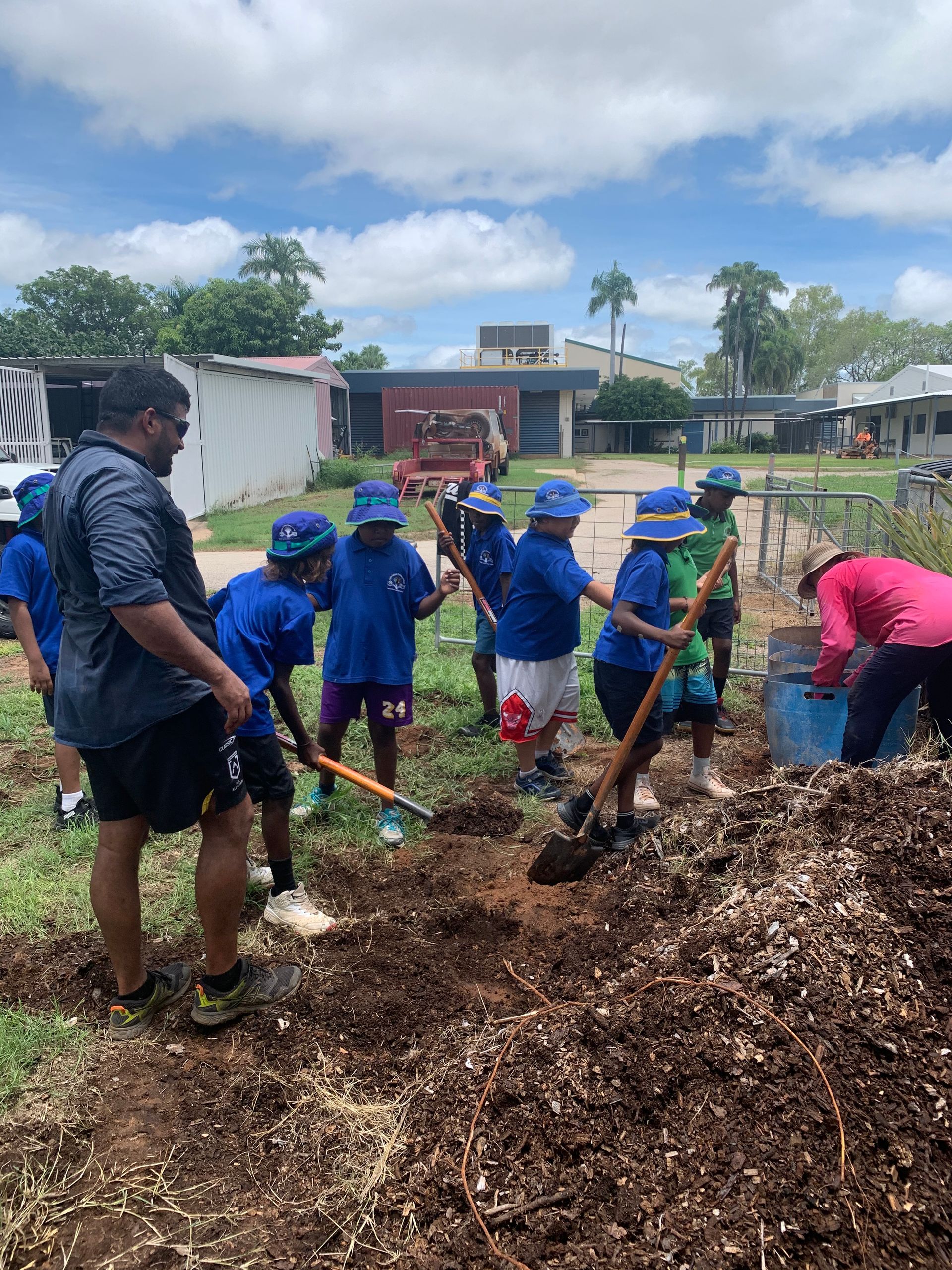 A group of children are digging in a pile of dirt.